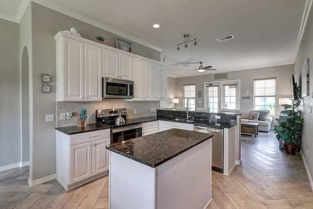 kitchen with visible vents, a peninsula, stainless steel appliances, arched walkways, and white cabinetry