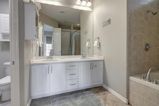 full bathroom featuring a sink, a relaxing tiled tub, tiled shower, and toilet