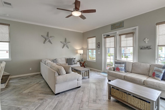 living area with visible vents, plenty of natural light, crown molding, and baseboards