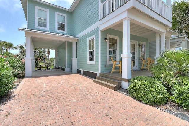 entrance to property featuring a standing seam roof, a porch, a balcony, and metal roof