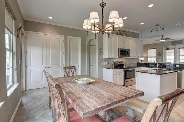 kitchen with decorative backsplash, arched walkways, appliances with stainless steel finishes, and white cabinets