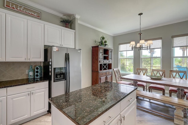 kitchen featuring white cabinetry, stainless steel fridge, an inviting chandelier, crown molding, and decorative backsplash