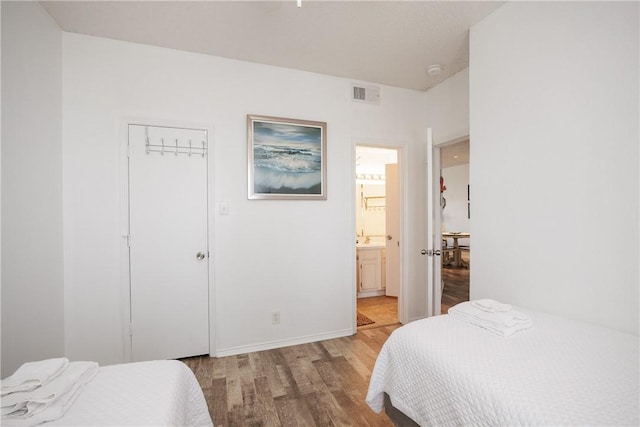 bedroom featuring connected bathroom, light hardwood / wood-style flooring, and a closet