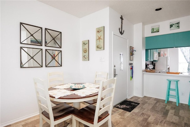 dining space featuring hardwood / wood-style floors and a textured ceiling