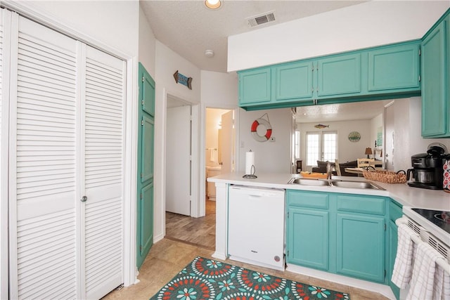 kitchen featuring sink, white appliances, kitchen peninsula, and a textured ceiling