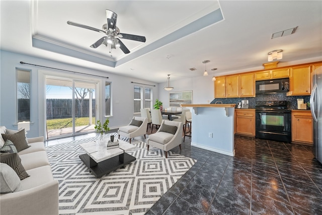 living room with a raised ceiling, ceiling fan, and crown molding