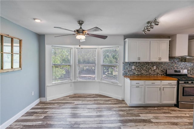 266 Lola Johnson Rd, Corpus Christi, TX 78418 - kitchen featuring stainless steel range with gas stovetop, wall chimney range hood, light wood-style flooring, butcher block counters, and ceiling fan