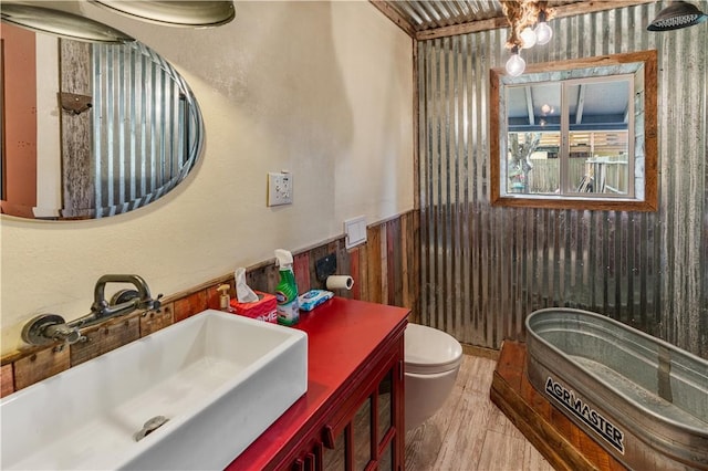 266 Lola Johnson Rd, Corpus Christi, TX 78418 - bathroom with a wainscoted wall, toilet, wood finished floors, vanity, and wooden walls