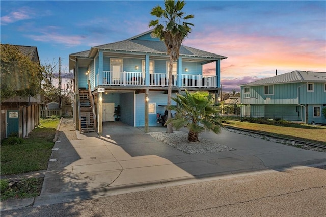1035 Sea Secret St, Port Aransas, TX 78373 - beach home featuring stairs, a shingled roof, covered porch, concrete driveway, and a carport