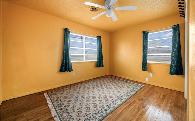 unfurnished room with hardwood / wood-style floors, ceiling fan, and a textured ceiling