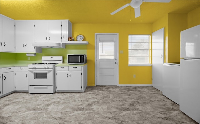 kitchen featuring white appliances, washer / clothes dryer, white cabinetry, and ceiling fan