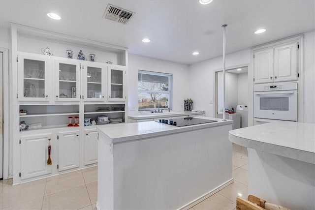 kitchen with white oven, light tile patterned floors, visible vents, and light countertops