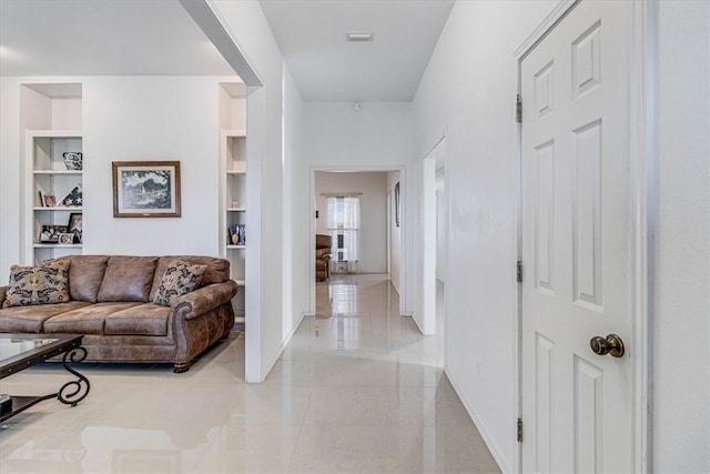 hall with light tile patterned floors, baseboards, and built in shelves