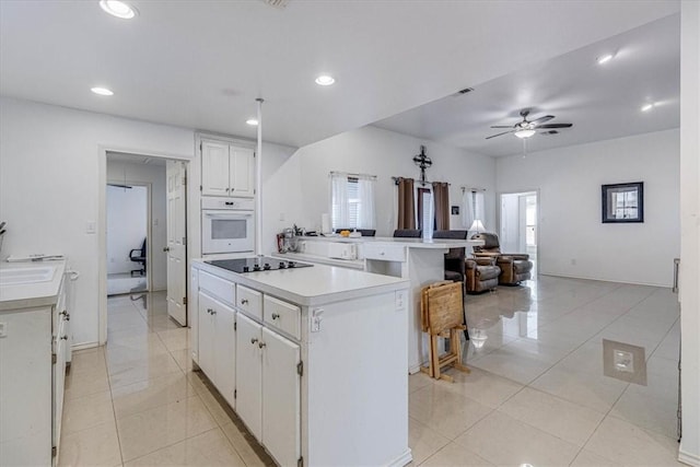 kitchen with ceiling fan, light countertops, open floor plan, oven, and black electric cooktop