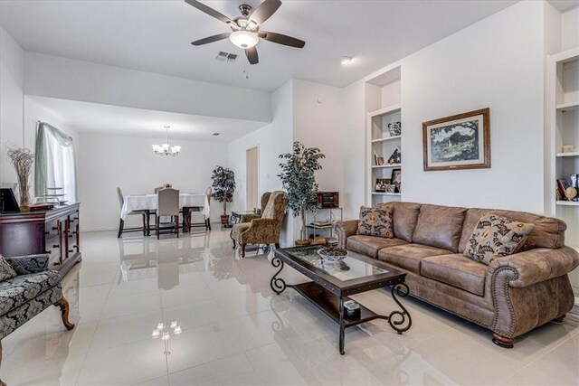 living area featuring tile patterned flooring, visible vents, ceiling fan with notable chandelier, and built in features
