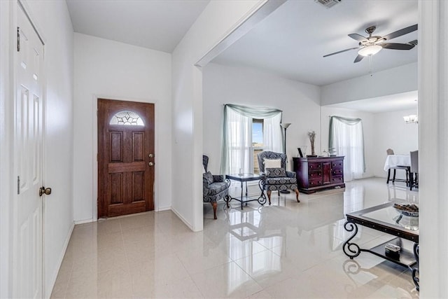 foyer featuring ceiling fan with notable chandelier, baseboards, and tile patterned flooring