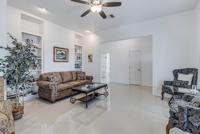 living room featuring built in shelves, visible vents, baseboards, and ceiling fan