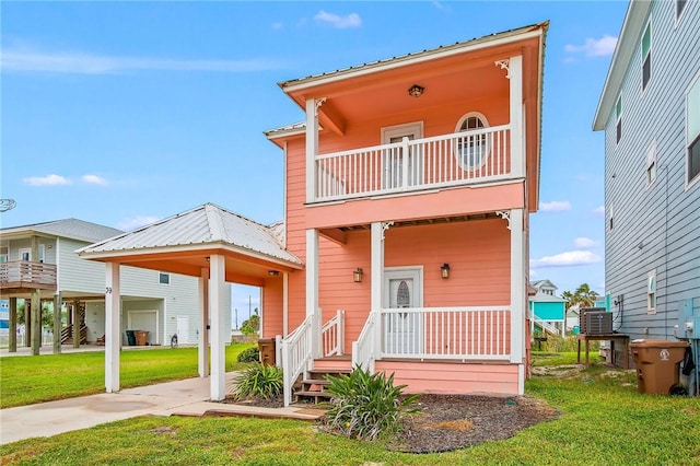 view of front facade with a balcony, cooling unit, and a front lawn