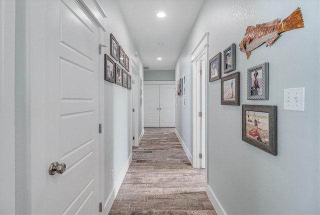 hallway with recessed lighting, wood finished floors, and baseboards