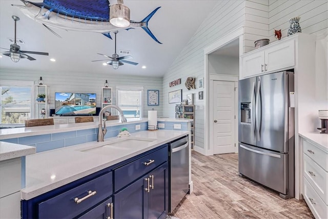 kitchen featuring vaulted ceiling, stainless steel appliances, a sink, and blue cabinets