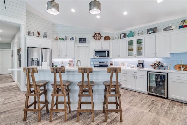 kitchen with light wood finished floors, decorative backsplash, lofted ceiling, wine cooler, and stainless steel appliances