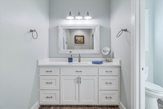 bathroom featuring toilet, baseboards, and vanity