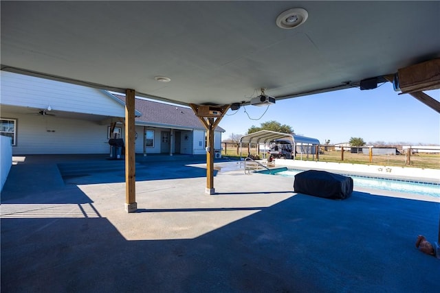 view of patio featuring a carport, a ceiling fan, fence, and a fenced in pool