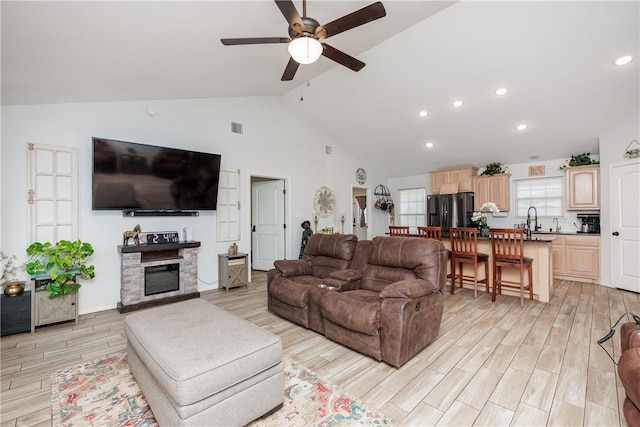 living room featuring sink, a fireplace, high vaulted ceiling, and ceiling fan