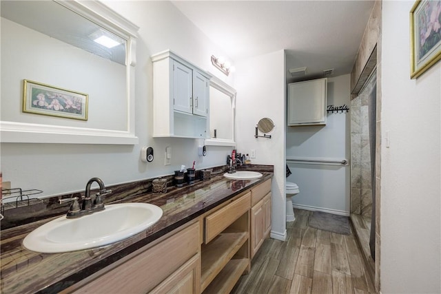 bathroom with toilet, double vanity, a sink, and wood finished floors