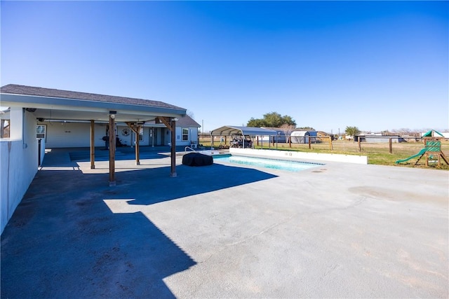 view of car parking featuring a carport, a playground, fence, and a fenced in pool