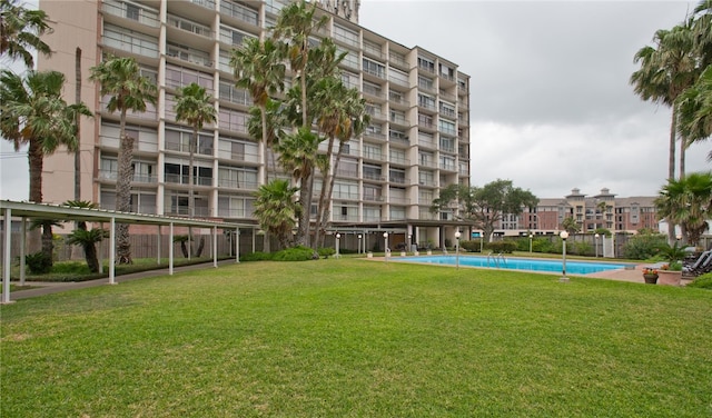 view of community featuring a swimming pool and a yard