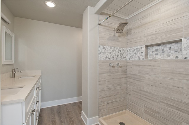 bathroom featuring hardwood / wood-style flooring, vanity, and tiled shower