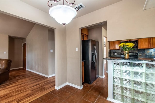 2725 Persimmon St, Corpus Christi, TX 78415 - kitchen featuring black appliances, brown cabinets, backsplash, dark countertops, and baseboards