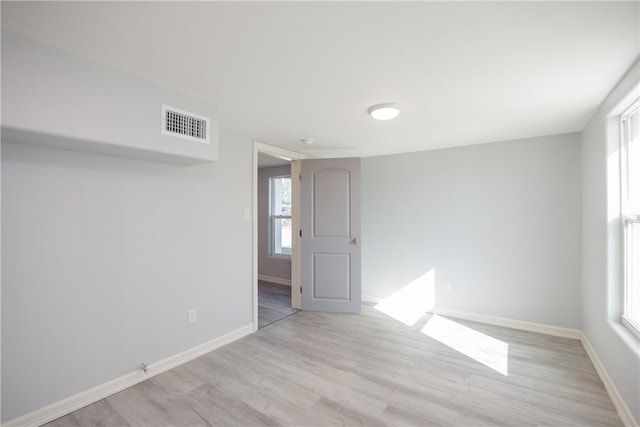 spare room with plenty of natural light and light hardwood / wood-style flooring