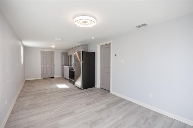 interior space with gray cabinets, stainless steel appliances, and light hardwood / wood-style flooring