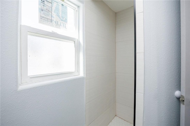 bathroom featuring a tile shower and plenty of natural light