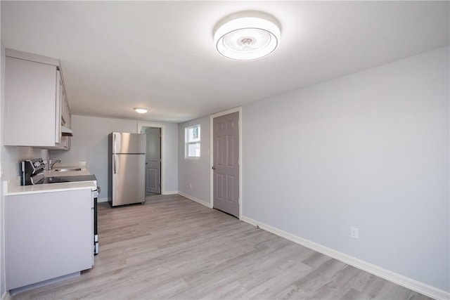 kitchen with stainless steel fridge, sink, light hardwood / wood-style floors, and range