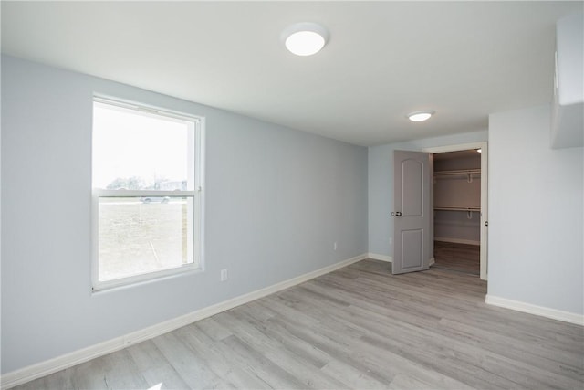 unfurnished bedroom featuring light hardwood / wood-style floors, a closet, a spacious closet, and multiple windows