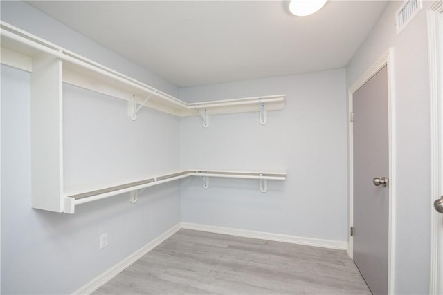 walk in closet with light hardwood / wood-style floors