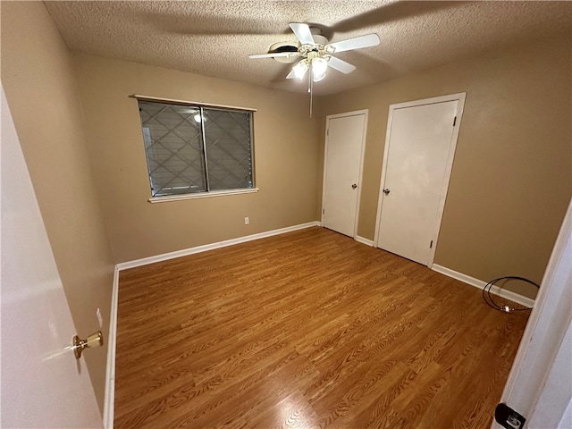 unfurnished bedroom with hardwood / wood-style floors, ceiling fan, and a textured ceiling