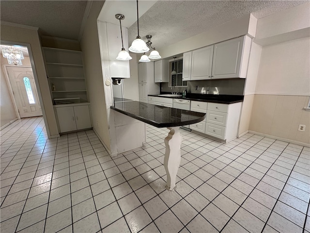 kitchen with white cabinets, kitchen peninsula, a textured ceiling, a kitchen breakfast bar, and decorative light fixtures