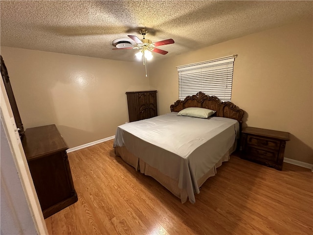 bedroom with a textured ceiling, ceiling fan, and light hardwood / wood-style flooring