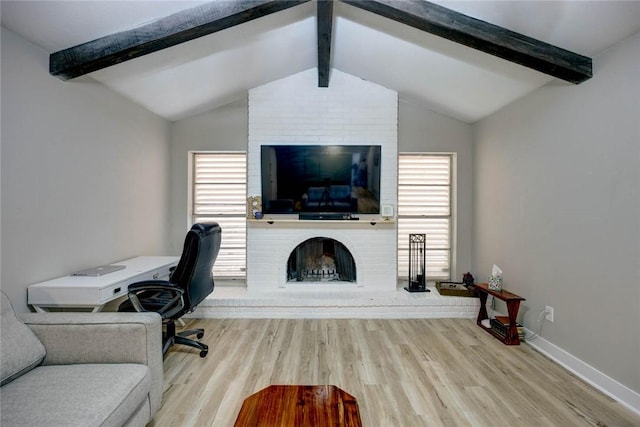 office space with a fireplace, lofted ceiling with beams, plenty of natural light, and light hardwood / wood-style floors