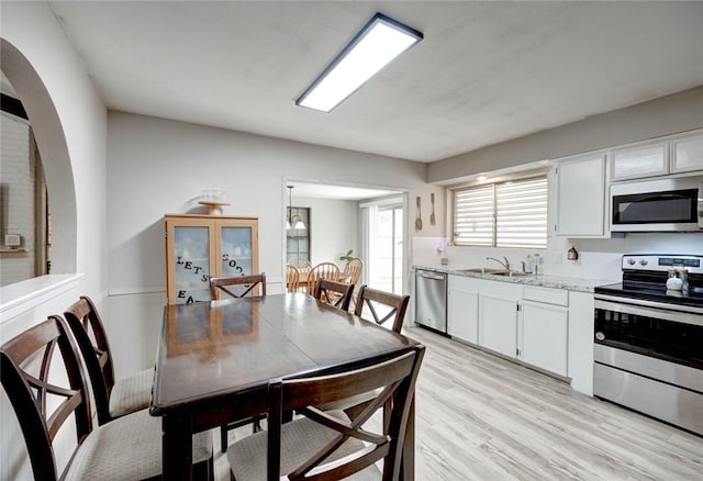 kitchen featuring white cabinetry, sink, light stone countertops, light hardwood / wood-style flooring, and appliances with stainless steel finishes