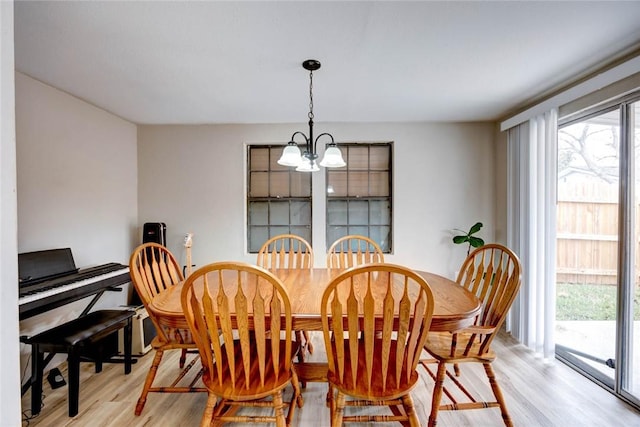 dining area with plenty of natural light, light hardwood / wood-style floors, and an inviting chandelier