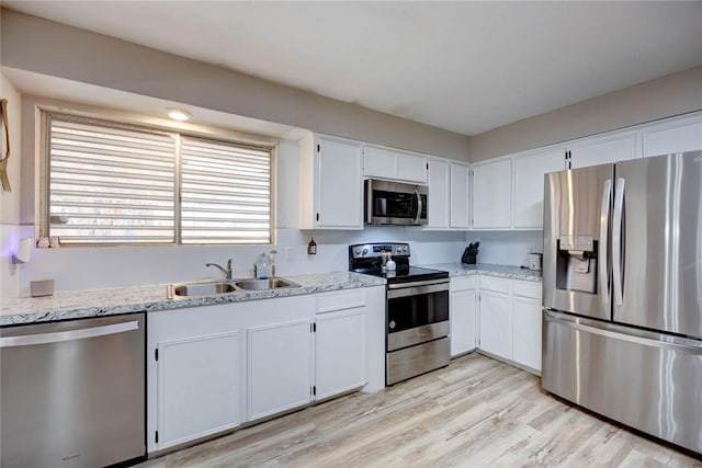 kitchen with light stone counters, white cabinetry, sink, and appliances with stainless steel finishes