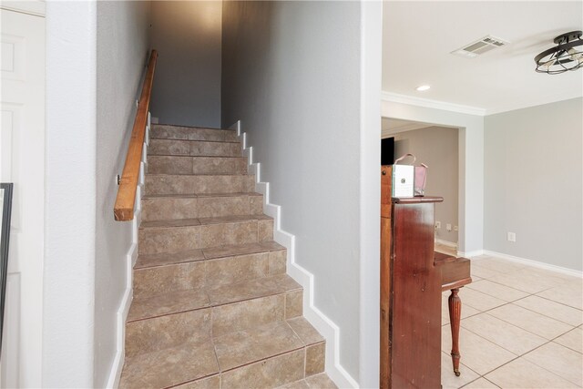 staircase with ornamental molding and tile patterned flooring