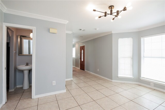 empty room with a wealth of natural light, a notable chandelier, light tile patterned flooring, and crown molding