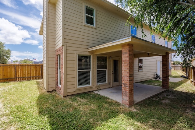 back of house with a lawn and a patio area