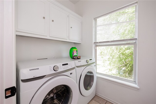 washroom with cabinets, light tile patterned floors, a healthy amount of sunlight, and washing machine and clothes dryer